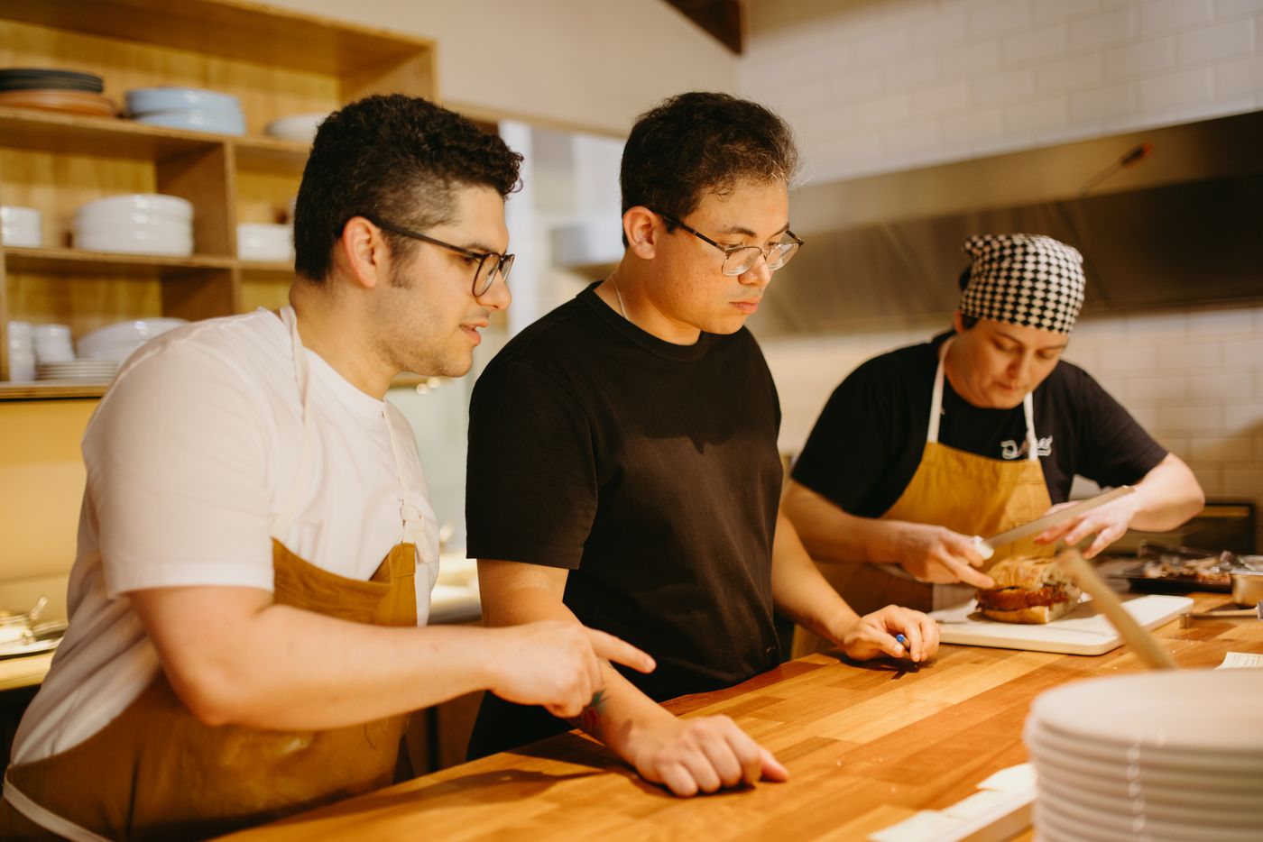 Trois collaborateurs préparent ensemble les assiettes en cuisine
