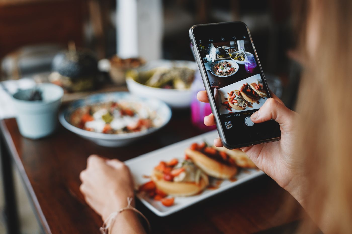 Une personne photographie ses plats avec un téléphone